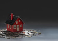 Real estate and property investment concept : small house model on stack of coins with black background